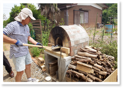 ピザ窯に薪をくべるご主人様 I様邸